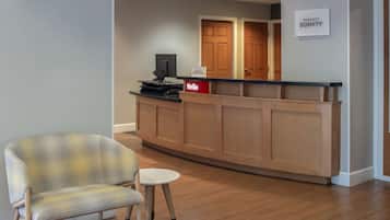 A reception area with a wooden reception desk, a flat-screen TV, a small round table, and a check-in counter.