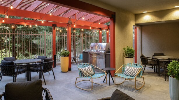Un espace extérieur aménagé en terrasse, avec un barbecue, des chaises et des tables en osier.