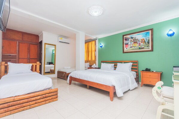 Une chambre d’hôtel avec deux lits, une tête de lit en bois, un mur d’accent vert, un tableau, une table de chevet et une petite table.