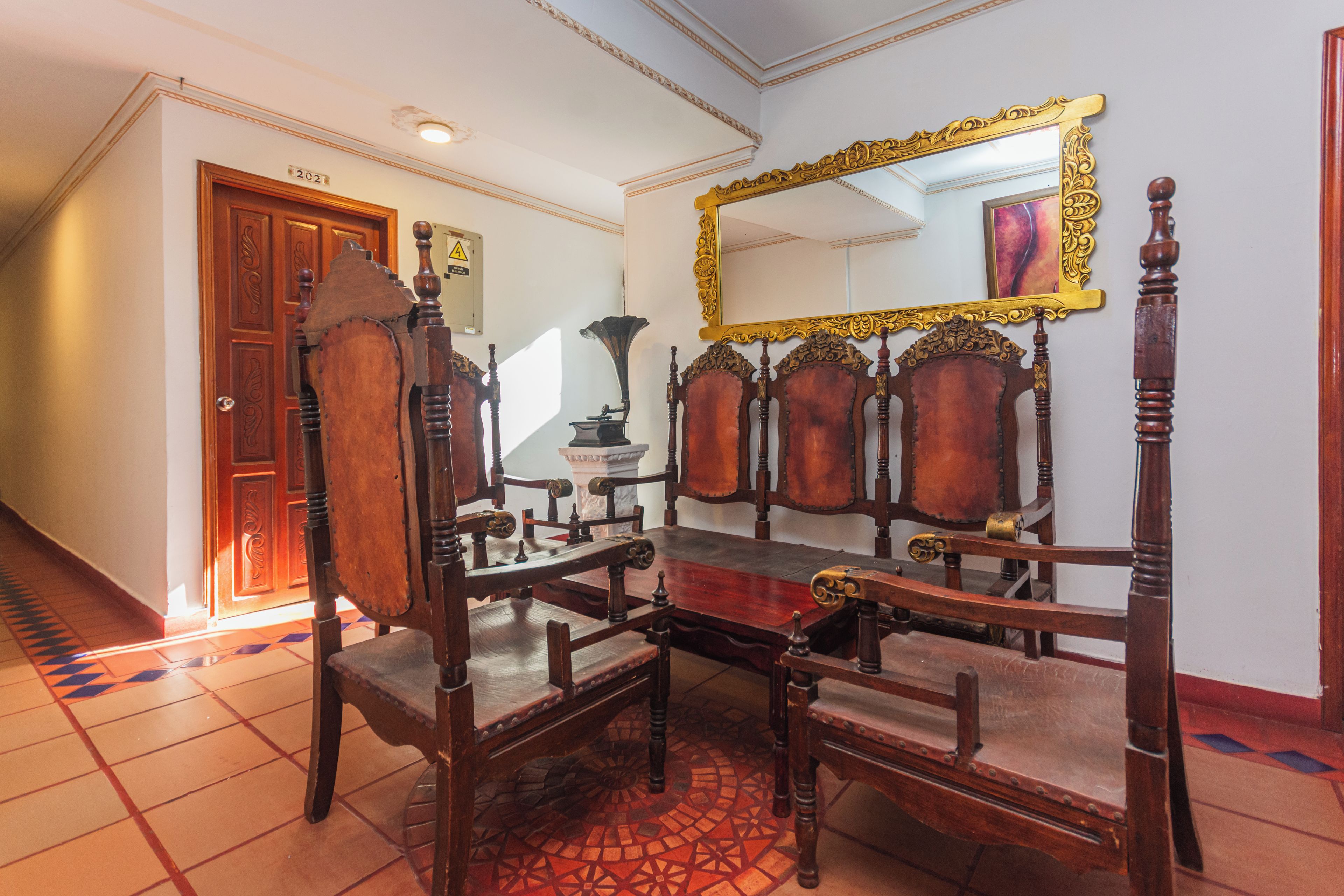 A traditional room with a wooden chair, a wooden table, and a mirror with an ornate frame.