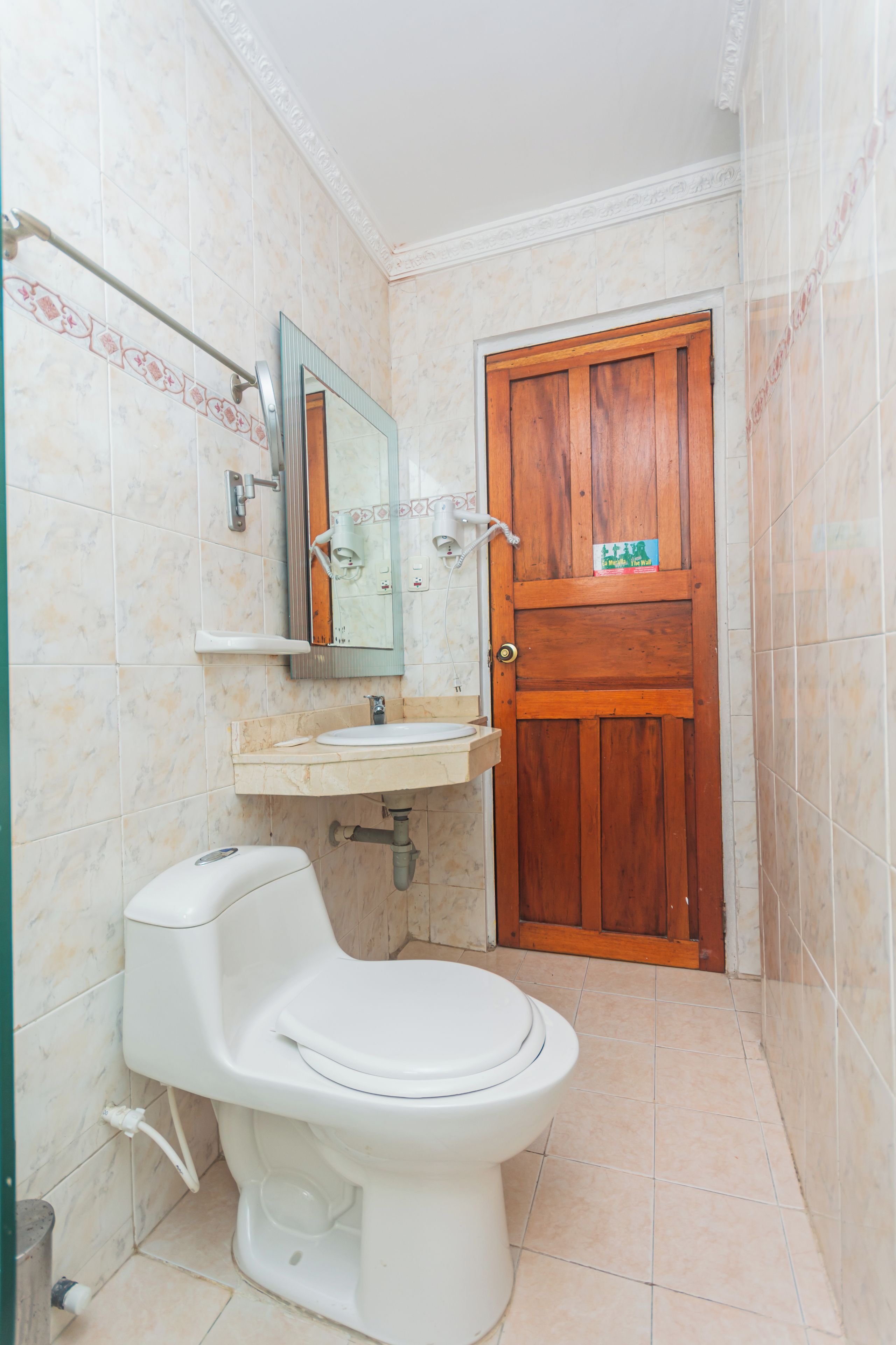Un baño con inodoro, lavamanos y puerta de madera.