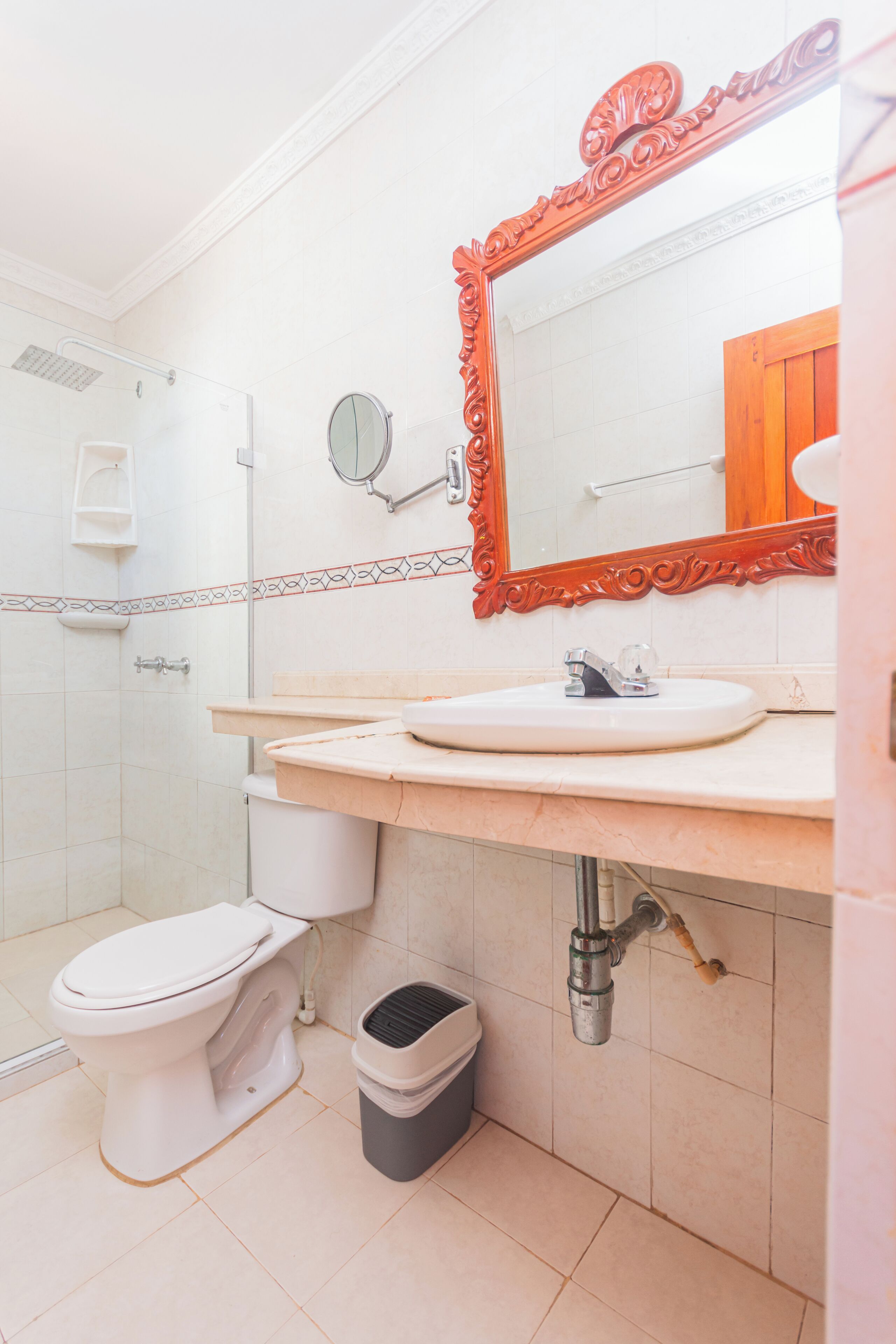A bathroom with a white toilet, a sink with a mirror above it, and a shower area.