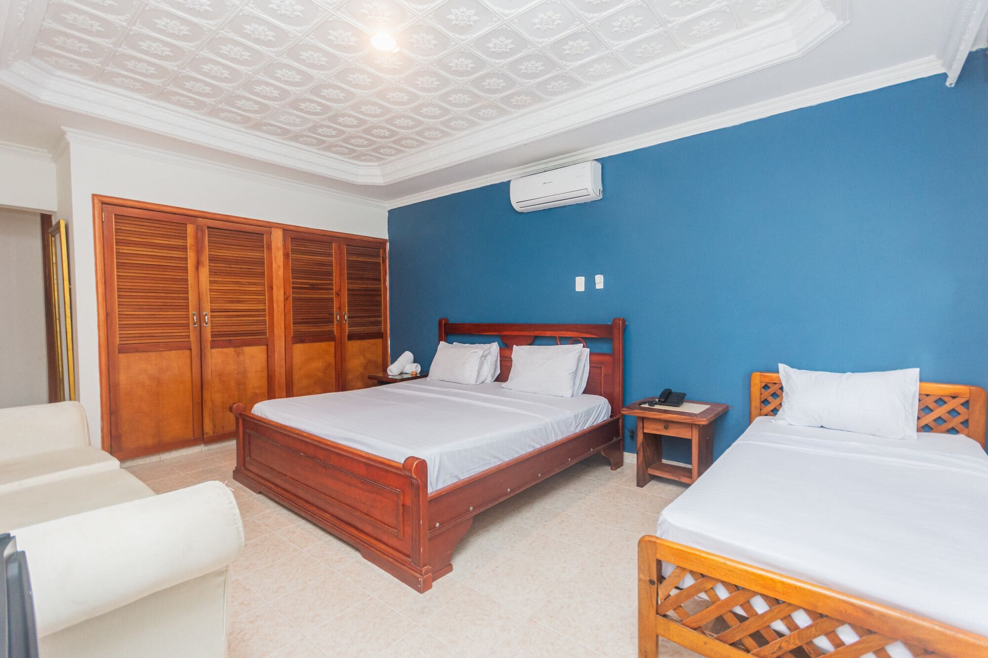 A bedroom with two beds, a wardrobe, and a ceiling fan.