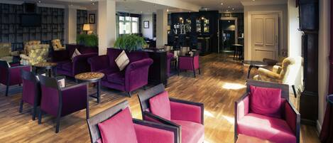 A spacious lobby with purple seating, a bar area, and a bookshelf.