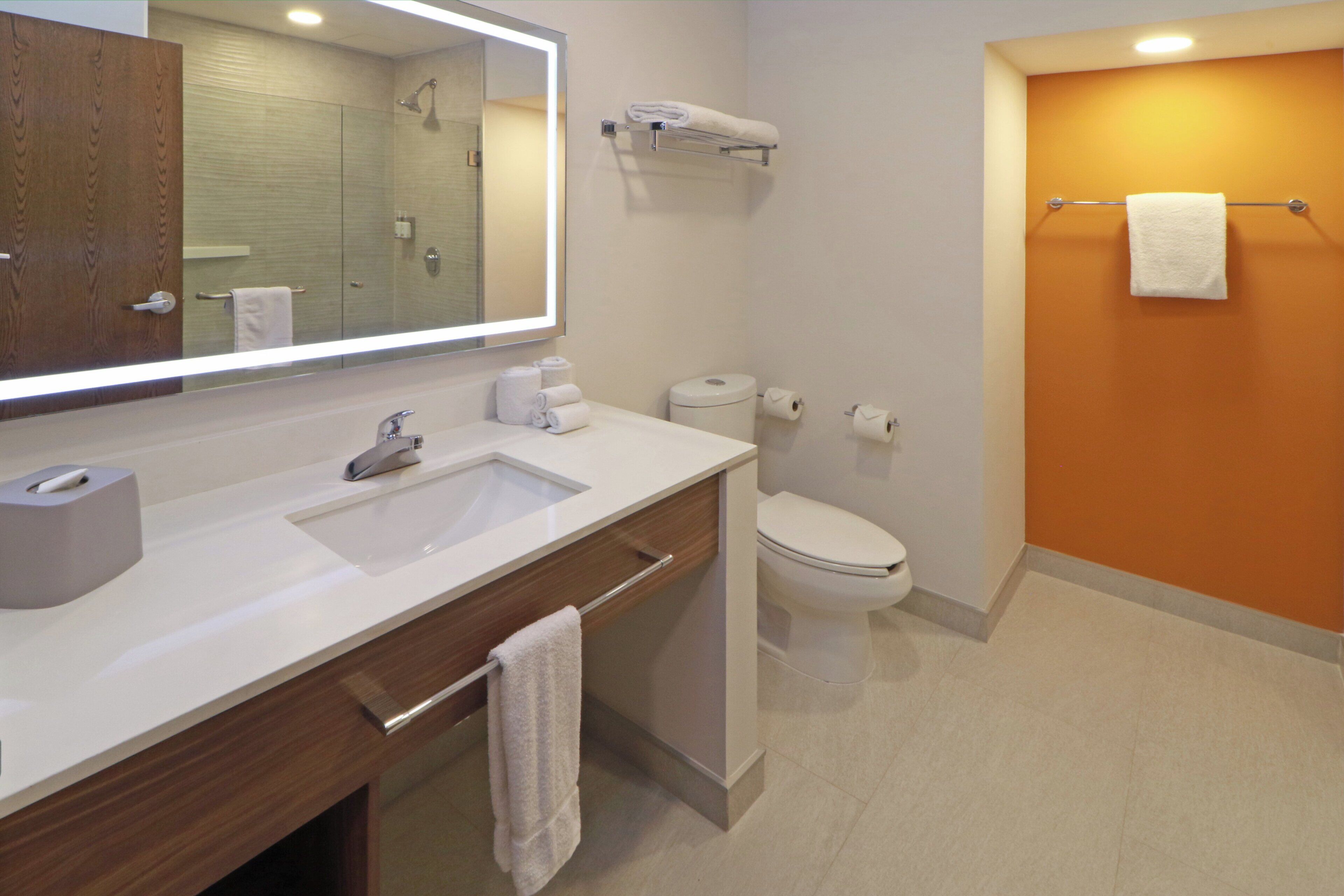 Une salle de bain moderne avec un grand miroir, un lavabo, des toilettes et une douche.