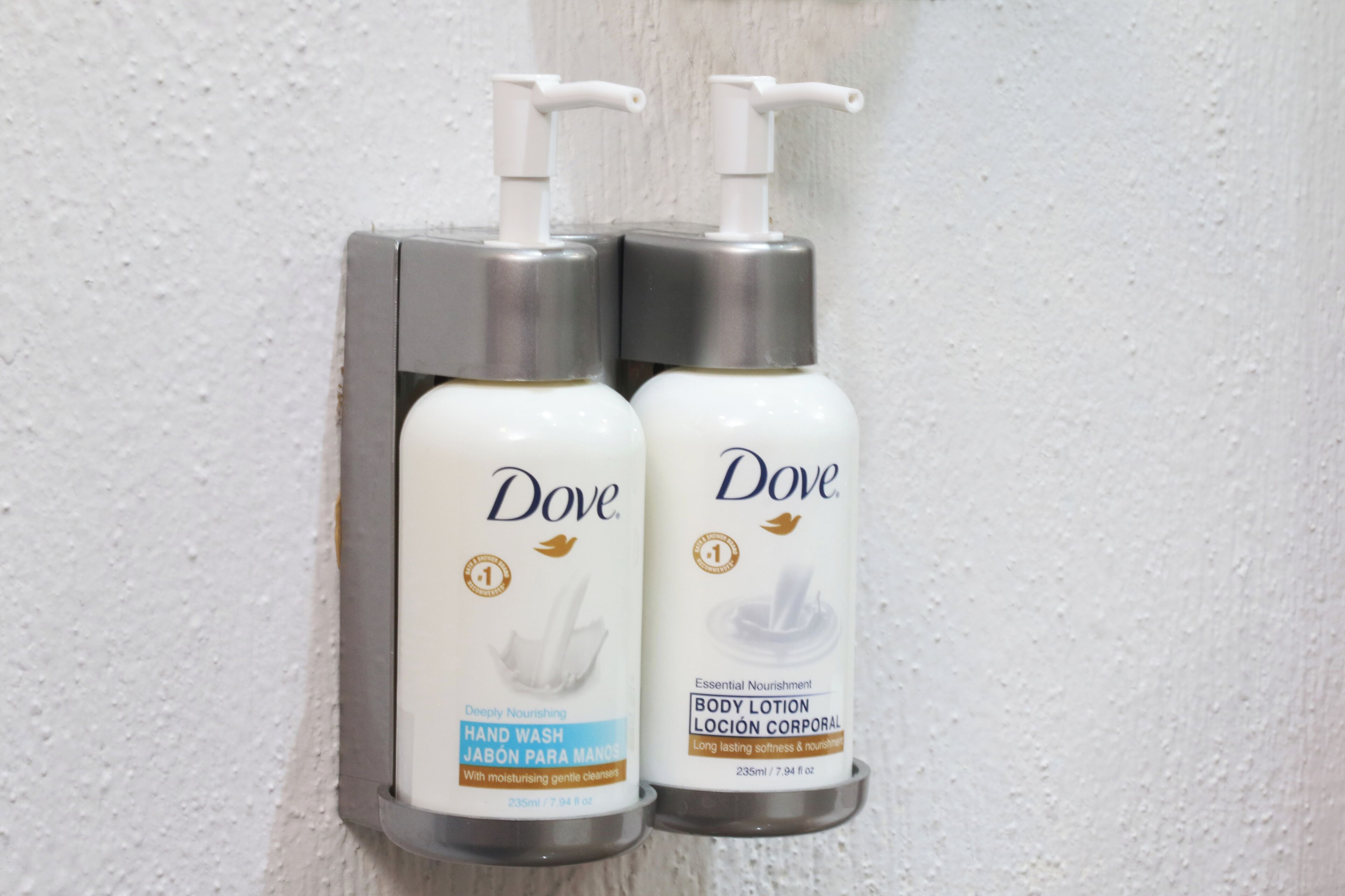 Two Dove hand wash and body lotion dispensers mounted on a wall.