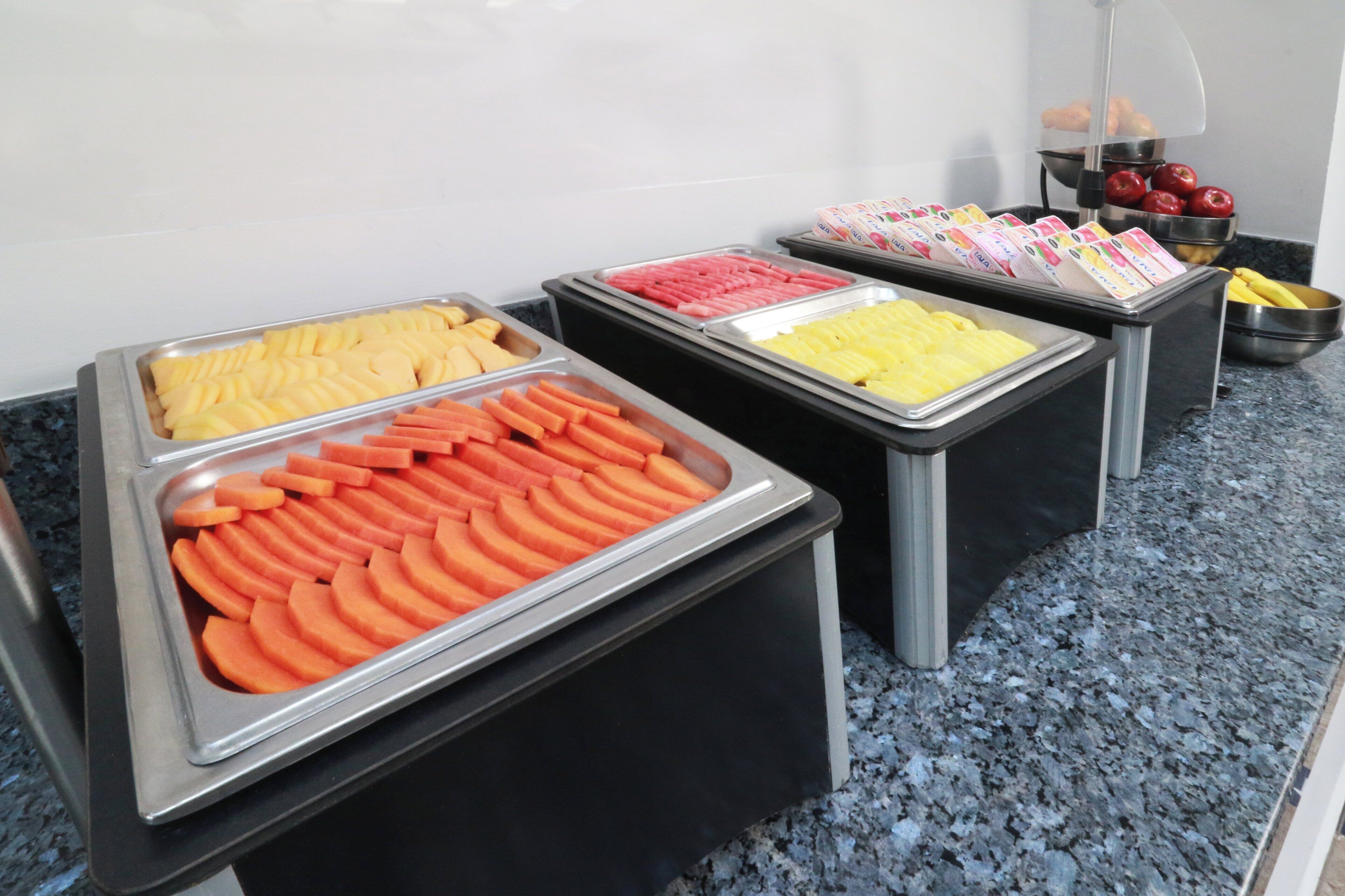 Un bufé con diversos alimentos presentados en bandejas.