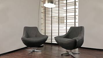 Dos sillones modernos con patas metálicas, frente a una pared con diseño de listones y una lámpara colgante.