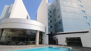 Ein modernes Gebäude mit Pool, großen Fenstern und einer geschwungenen Struktur.