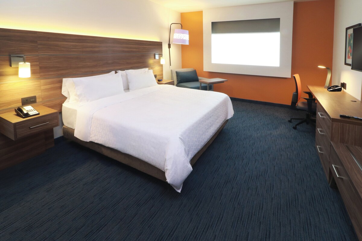 A hotel room with a large bed, bedside tables, a desk, and a chair.