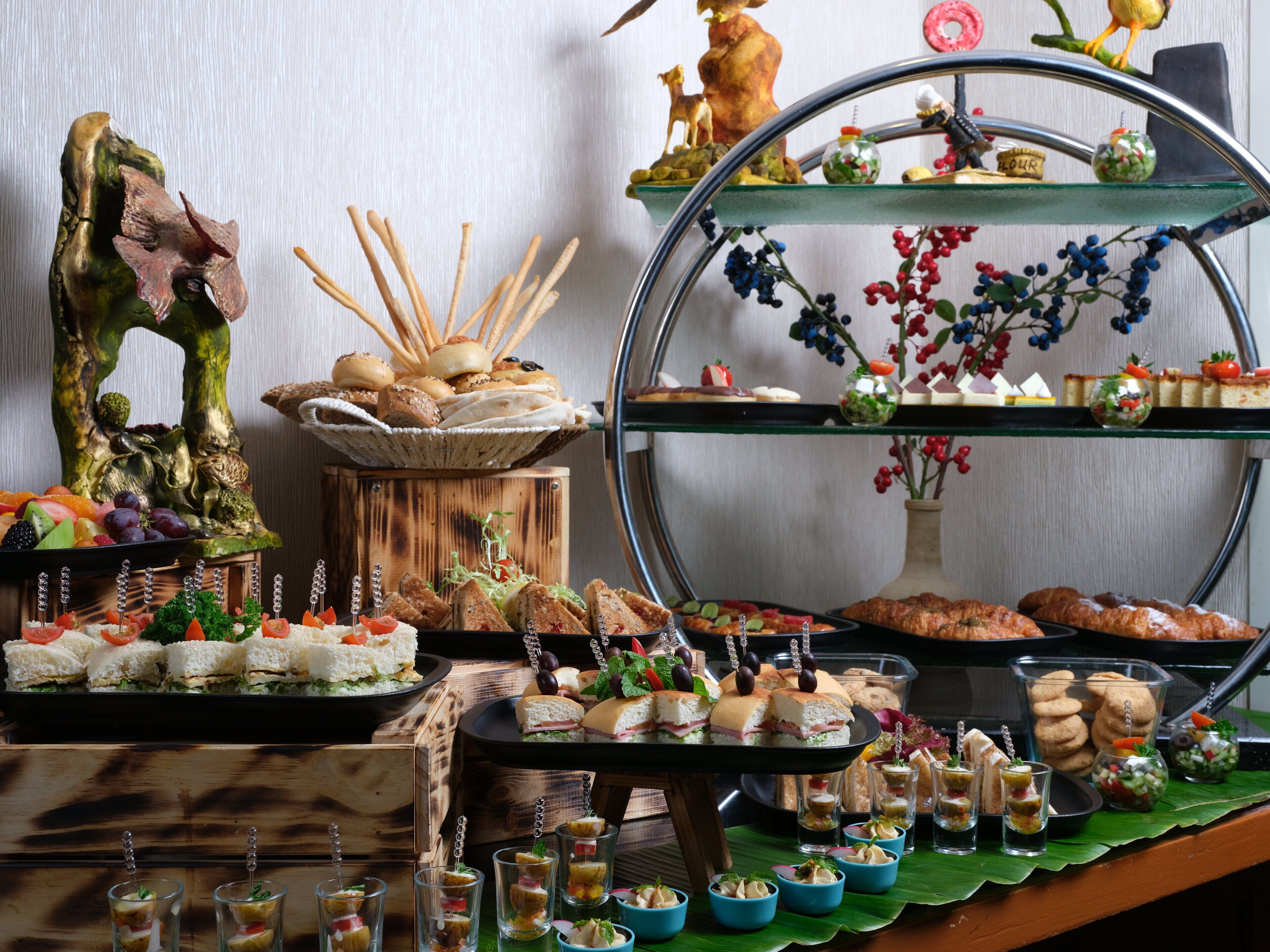A buffet with various food items, including sandwiches, desserts, and appetizers.
