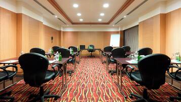 A conference room with a patterned carpet, wooden panel walls, and black office chairs.