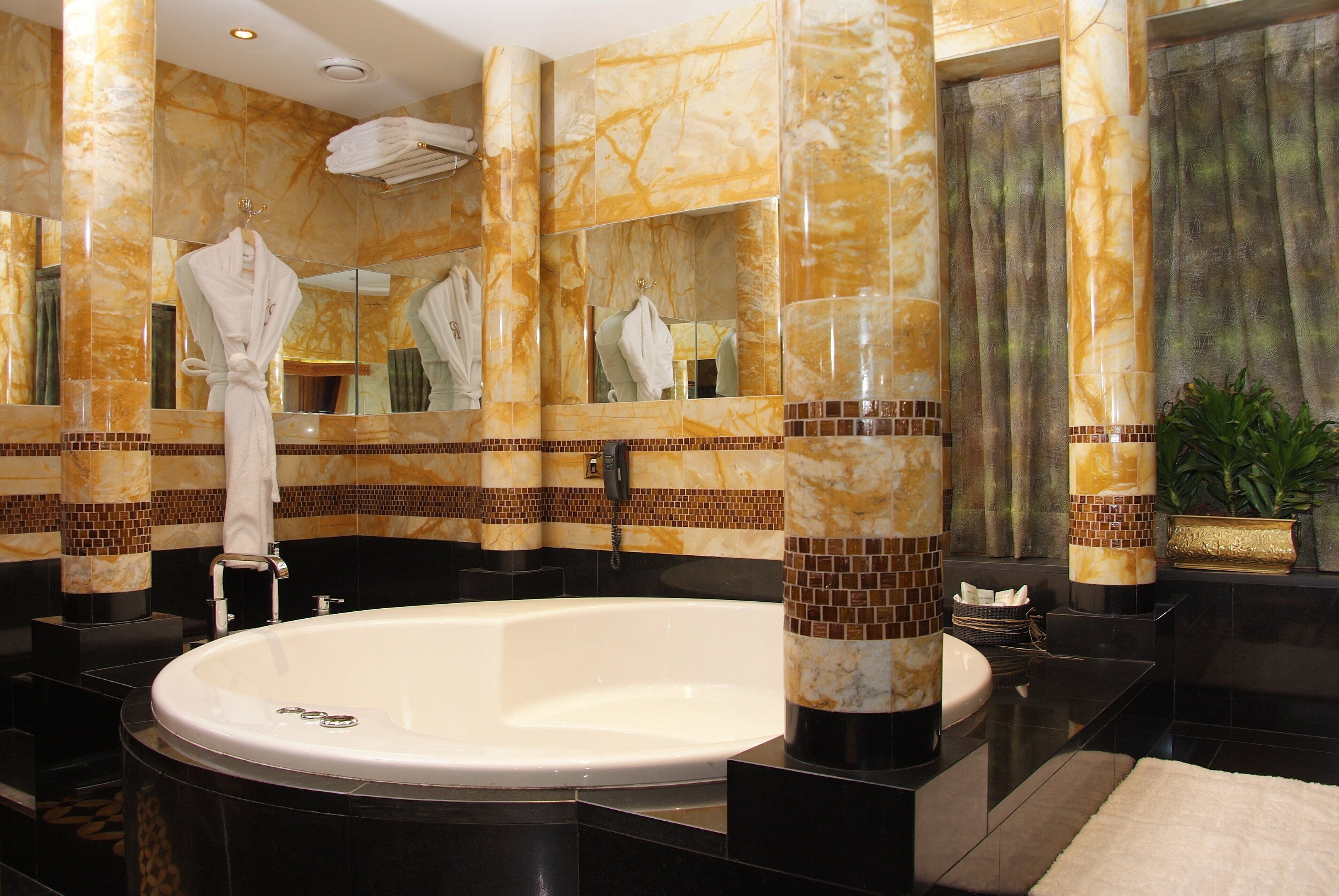 Une salle de bain luxueuse avec une grande baignoire, des colonnes en marbre et un espace coiffeuse.