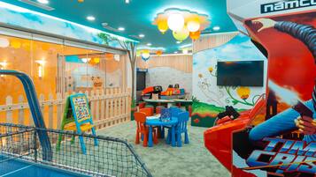 Kids can play and relax in the Kids Club RAINBOW area, featuring a playpen, table, chairs, and colorful mural.