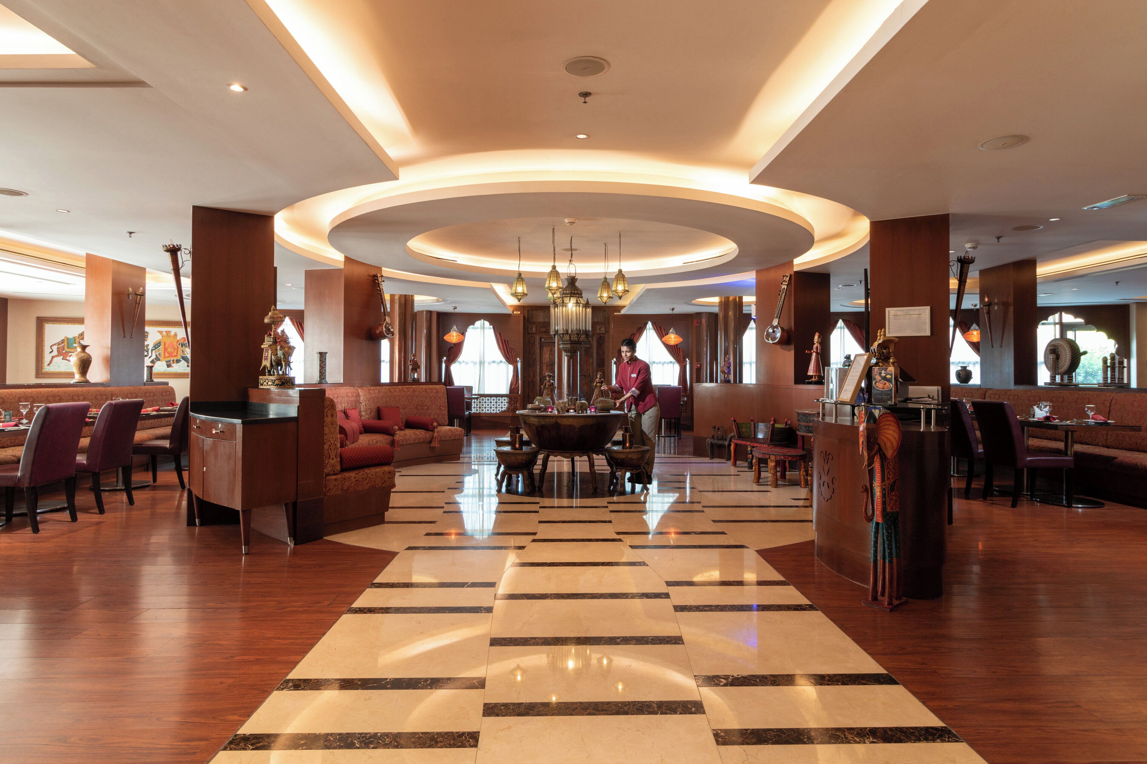 Un'area di accoglienza di un hotel con una zona salotto centrale, un bar e un lampadario.