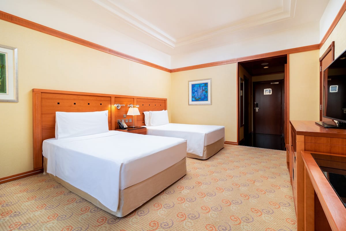 A hotel room with two beds, a television, and a desk.