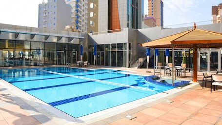 Una piscina al aire libre, tumbonas. Holiday Inn Kuwait by IHG