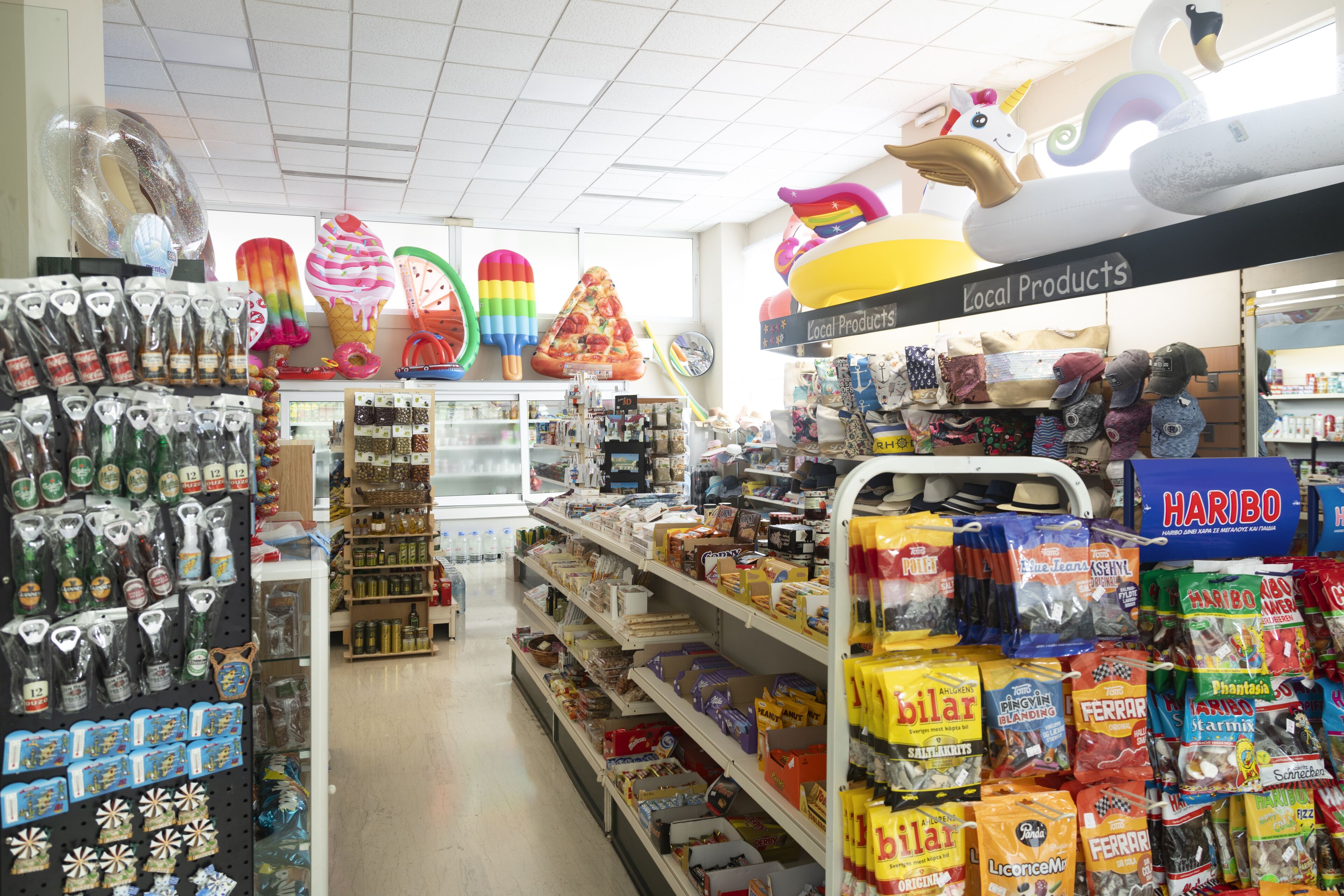 Tienda con estantes llenos de aperitivos, bebidas y productos locales.