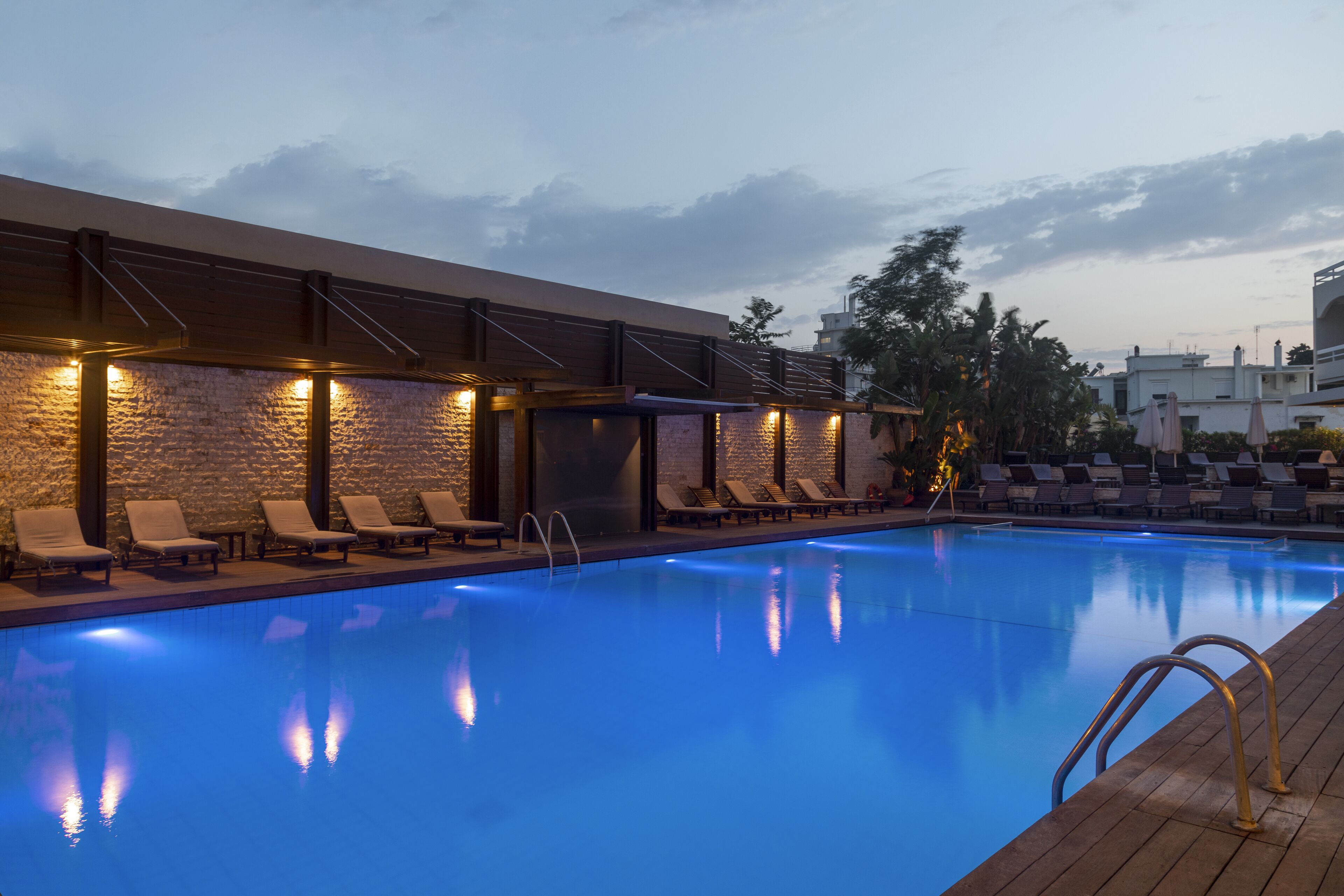 A swimming pool with lounge chairs and a covered area with lights.