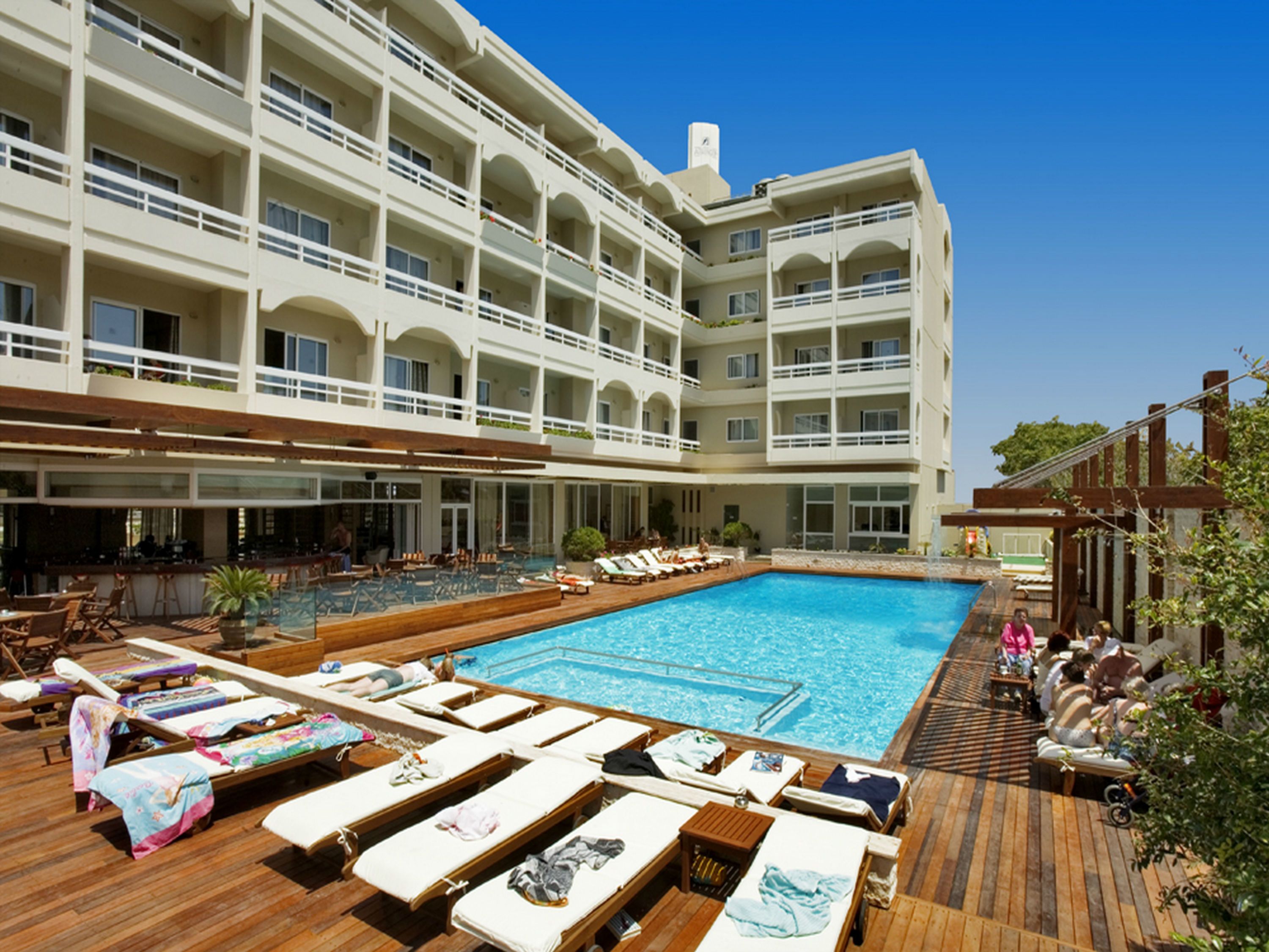 Un hôtel à plusieurs étages doté d’une grande piscine, d’un espace extérieur aménagé et d’un bar.