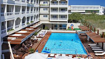 Un hôtel doté d’une grande piscine, de nombreux balcons et d’un espace extérieur aménagé pour s’asseoir.