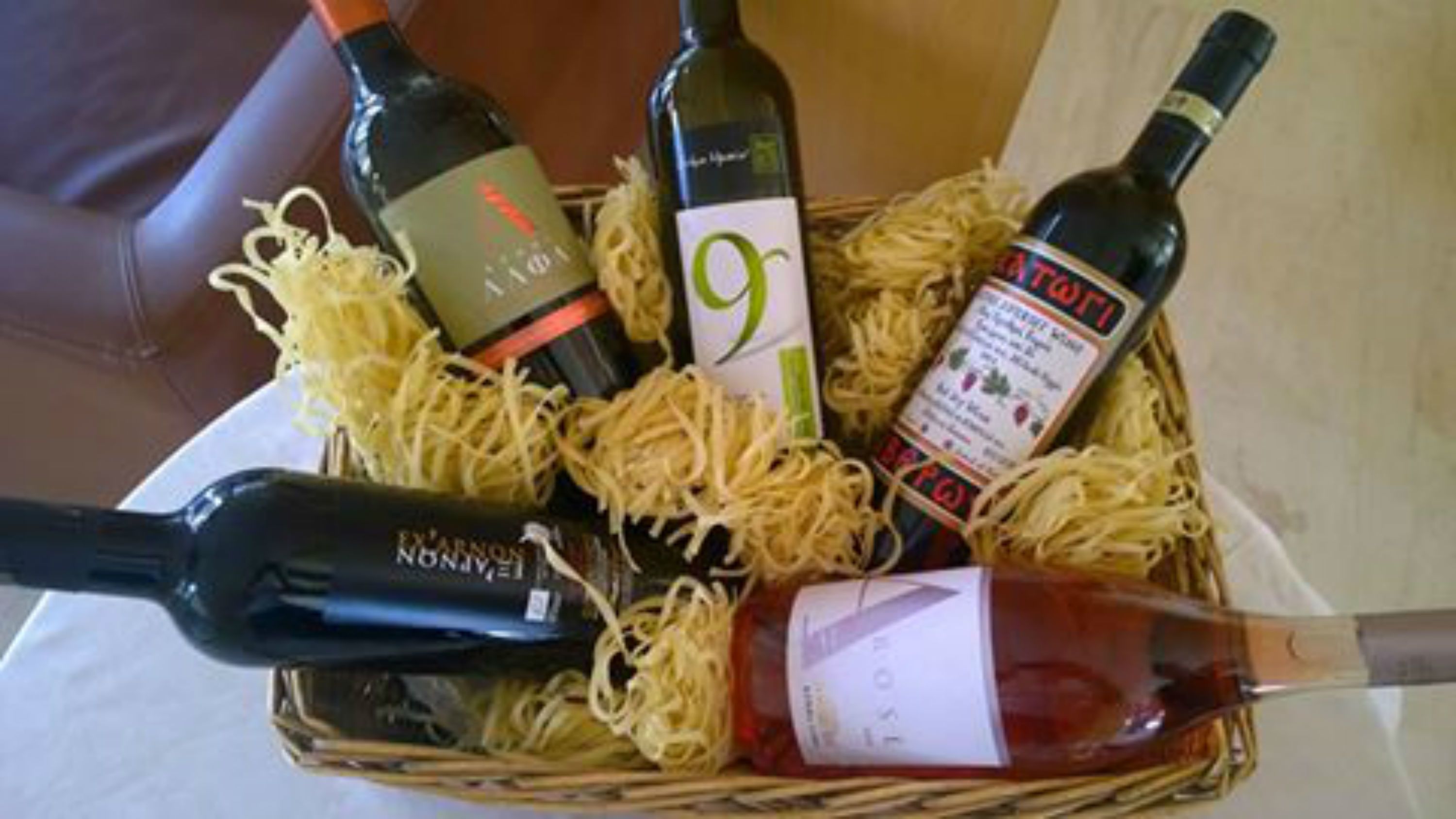 Un panier contenant différentes bouteilles de vin et une boîte de spaghettis.