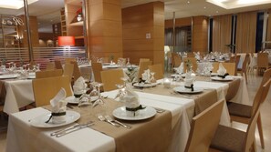 A banquet hall with tables set for a formal event, featuring white tablecloths, neatly arranged cutlery, and elegant centerpieces. - Athineon Hotel (Rhodes)