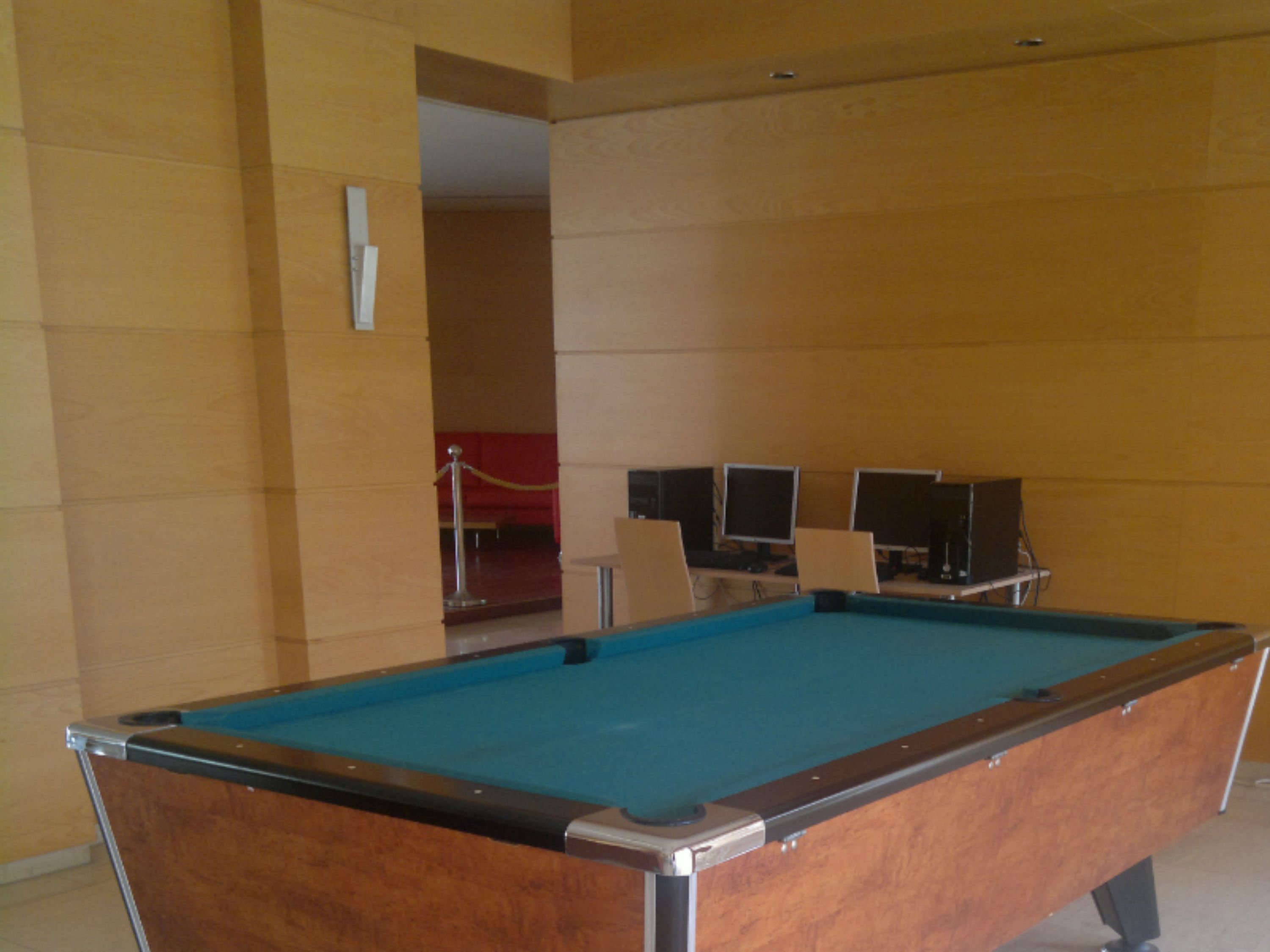 Une table de billard dans une pièce aux murs de couleur beige et au tapis rouge.