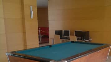 Une table de billard dans une pièce aux murs de couleur beige et au tapis rouge.