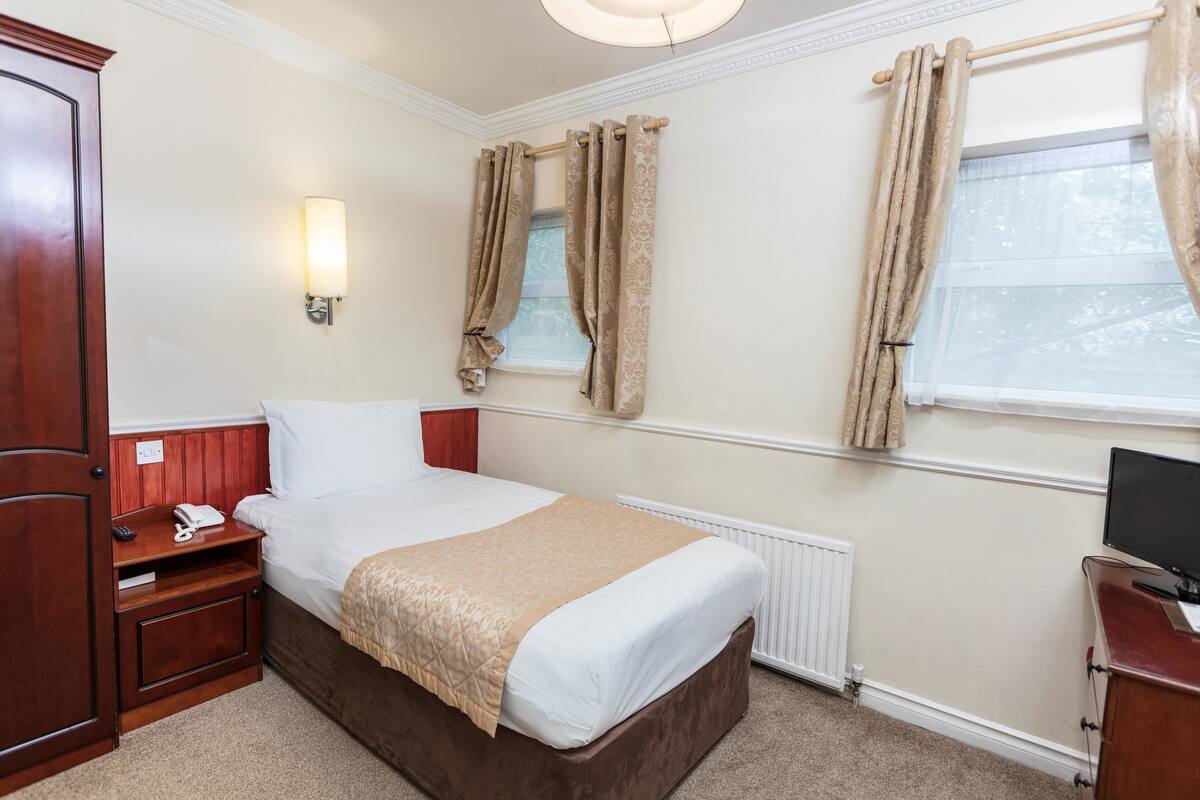 A neatly arranged bedroom with a large bed, bedside tables, a wardrobe, and a television.
