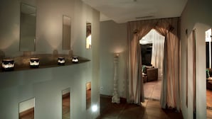 Un pasillo con un espejo, un candelabro alto y un sofá al fondo.