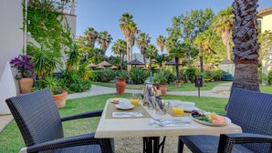 Un espacio de comedor al aire libre con sillas de mimbre, una mesa dispuesta para el desayuno y un cartel que indica un spa cercano.
