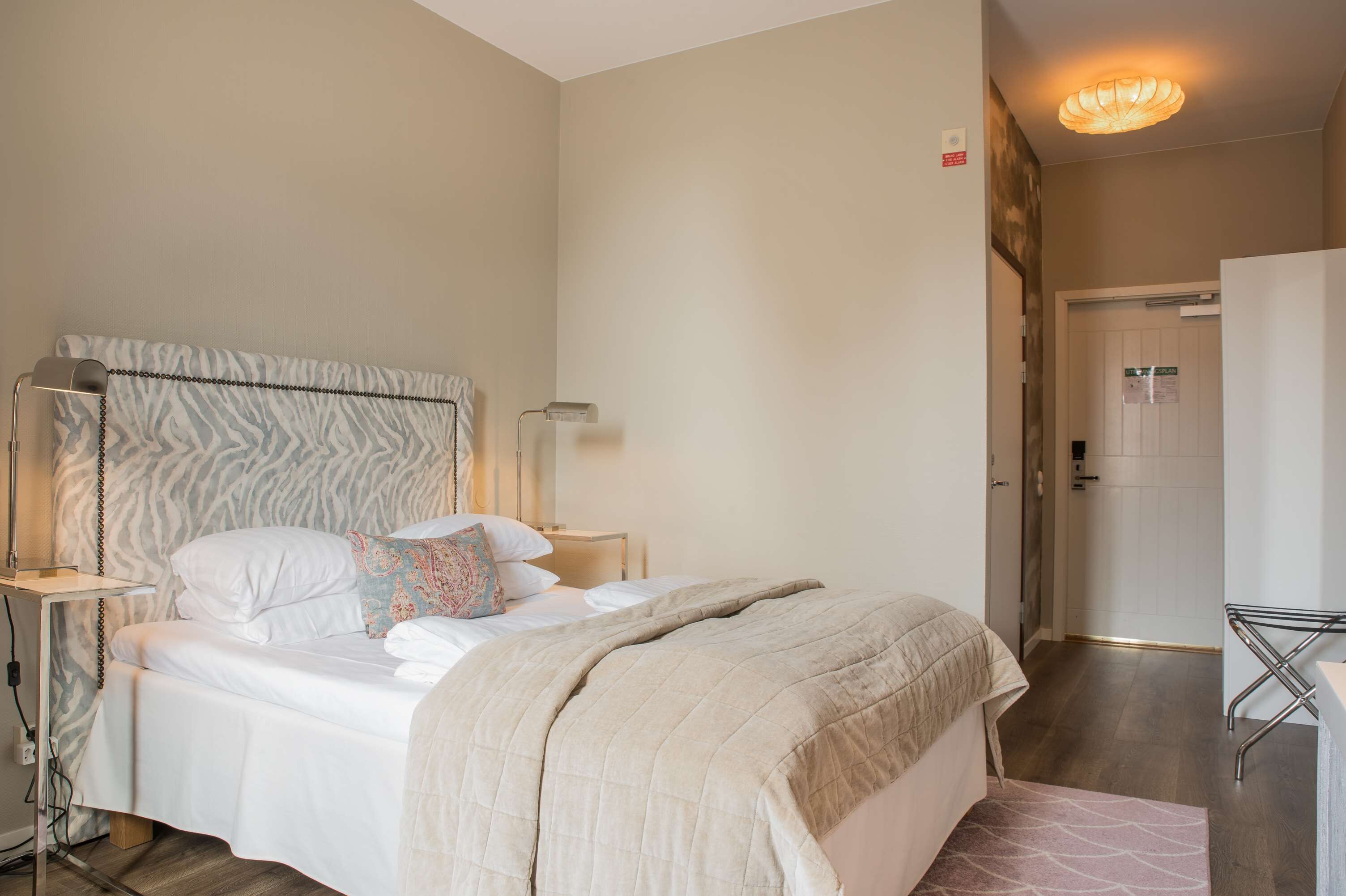A neatly made bed with a zebra-patterned headboard, bedside lamps, and a bedside table.