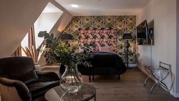 Et soveværelse med en seng, en stol, et bord og en væg med geometrisk mønster.