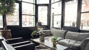 A modern living room with a grey sofa, black leather armchairs, a wooden coffee table, and a potted plant.