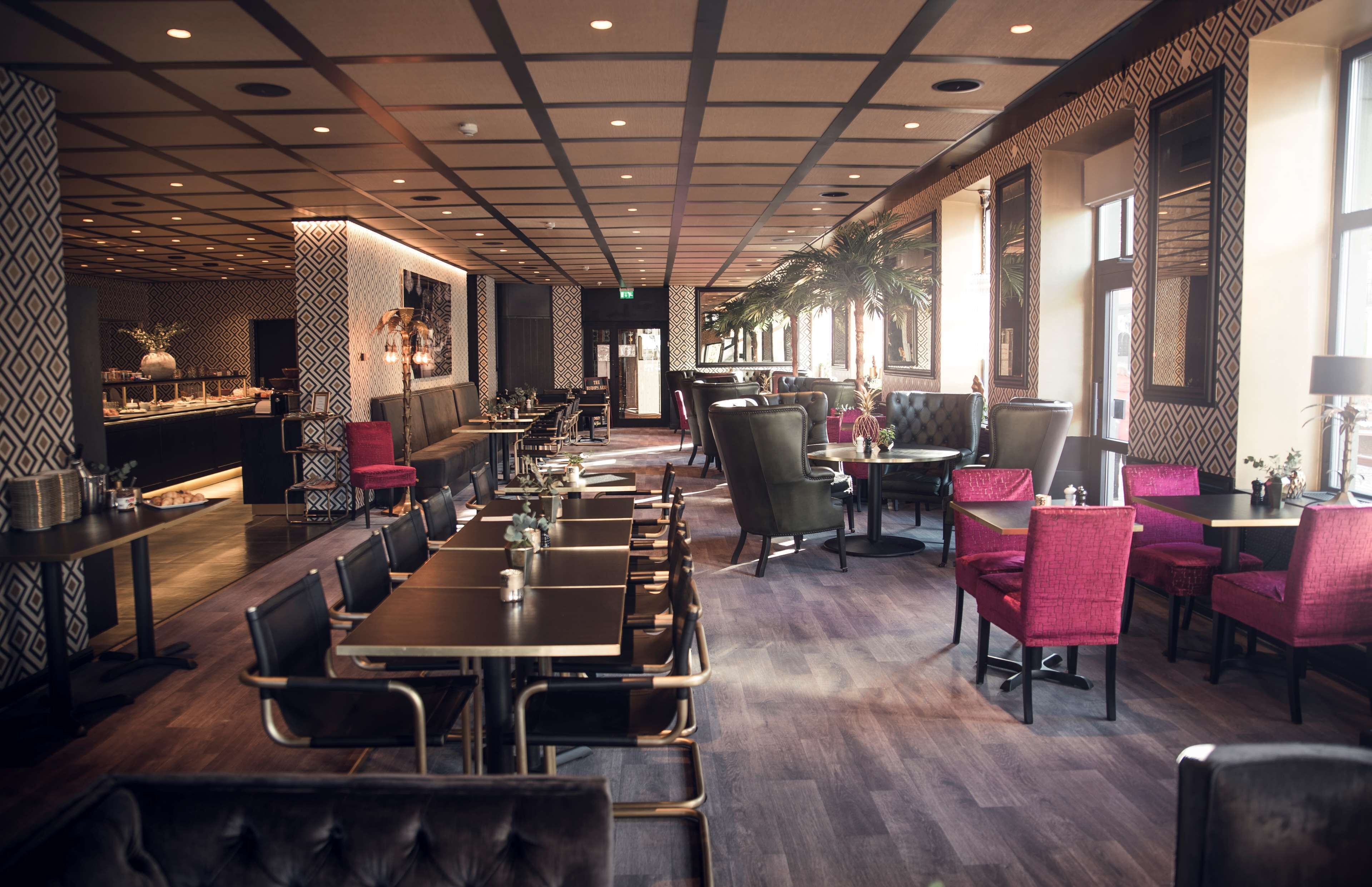 A restaurant with a long counter, multiple tables, and chairs.
