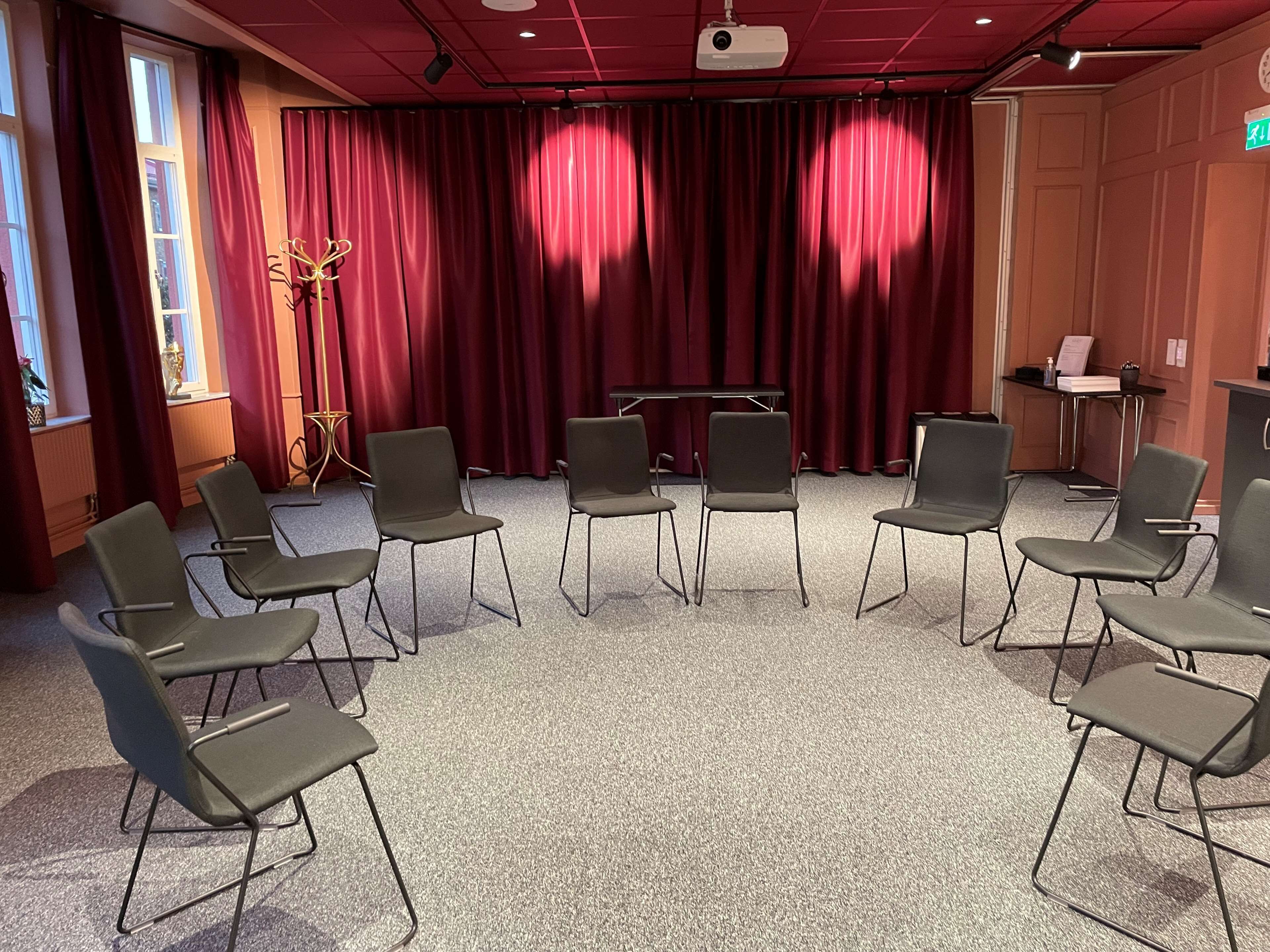 A conference room with a stage, red curtains, and a projector.