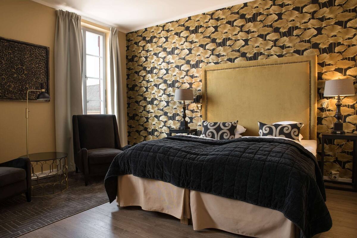 Une chambre d’hôtel avec un grand lit, une chaise, une petite table et une lampe.