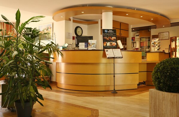 A reception area with a curved desk, a clock, and informational posters.