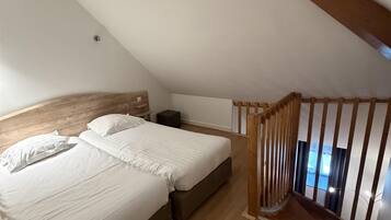 A bedroom with a wooden bed, a nightstand, and a sloped ceiling.