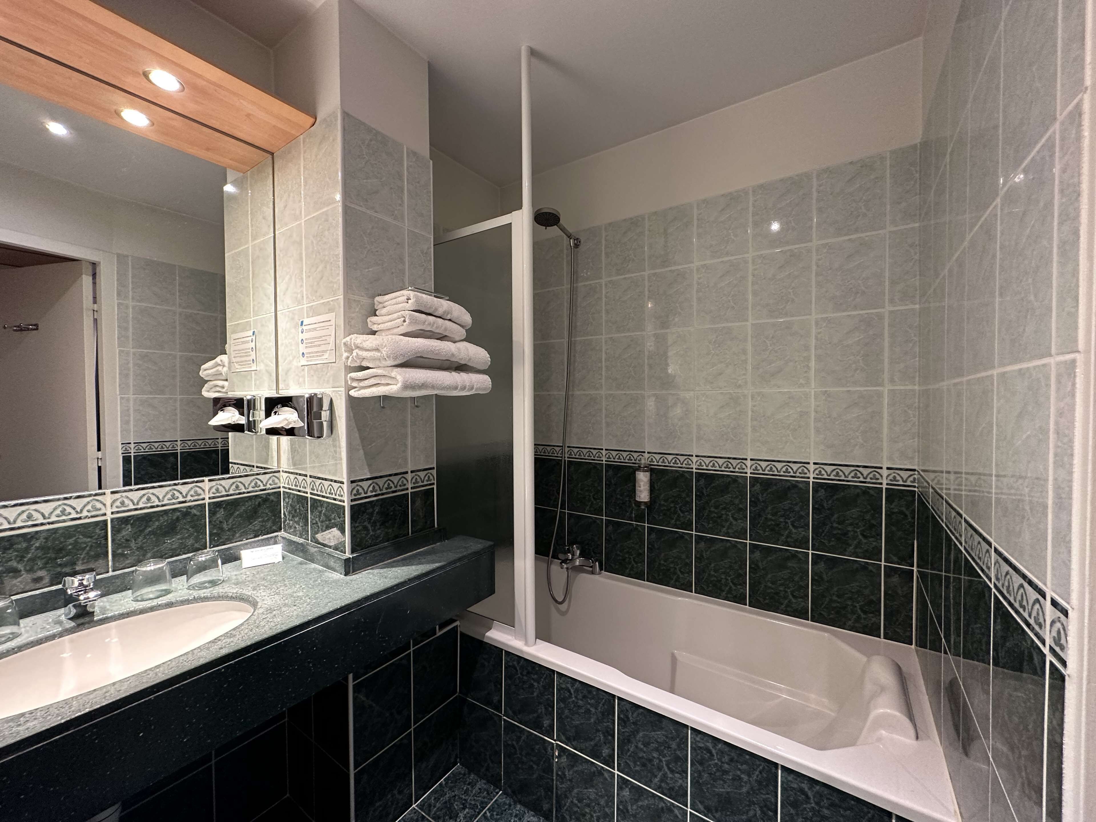A modern bathroom with a large mirror, a sink, a bathtub, and a shower.