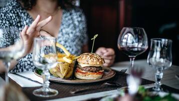 Ein Esstisch mit einem Burger, Pommes und Weingläsern.