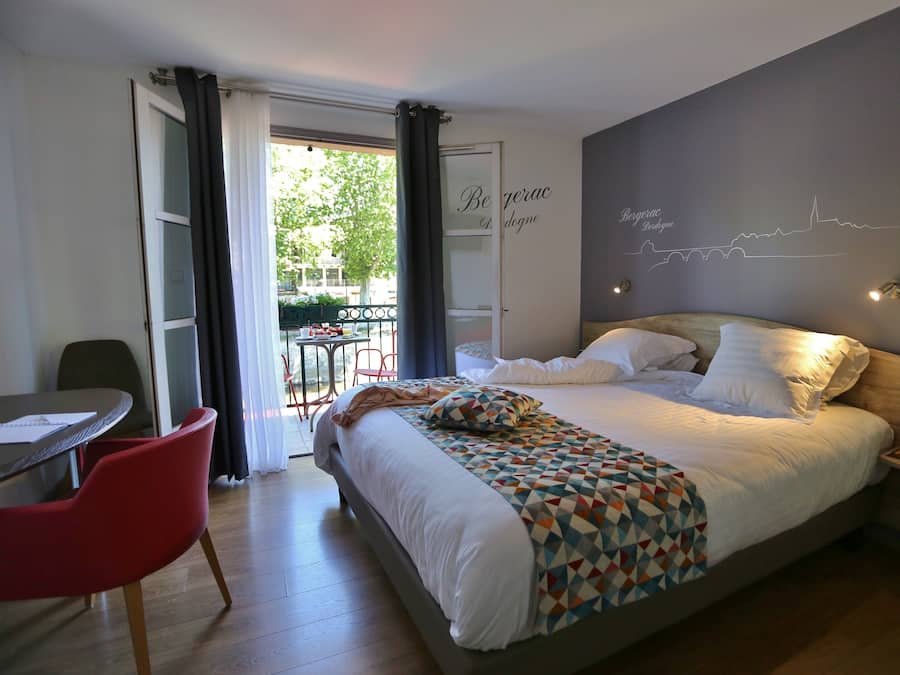 A modern hotel room with a large bed, a desk, and a chair.