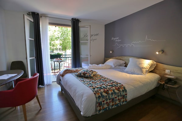 A modern hotel room with a large bed, a desk, and a chair.