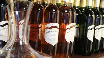A row of wine bottles with labels, a clear wine glass, and a wooden shelf.