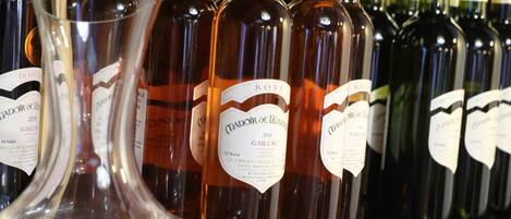 A row of wine bottles with labels, a clear wine glass, and a wooden shelf.