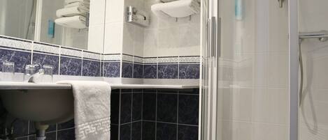 A modern bathroom with a glass-enclosed shower, a sink with a towel, and a mirror.