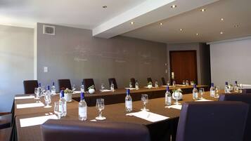 A conference room with a long table, chairs, water bottles, and glasses.