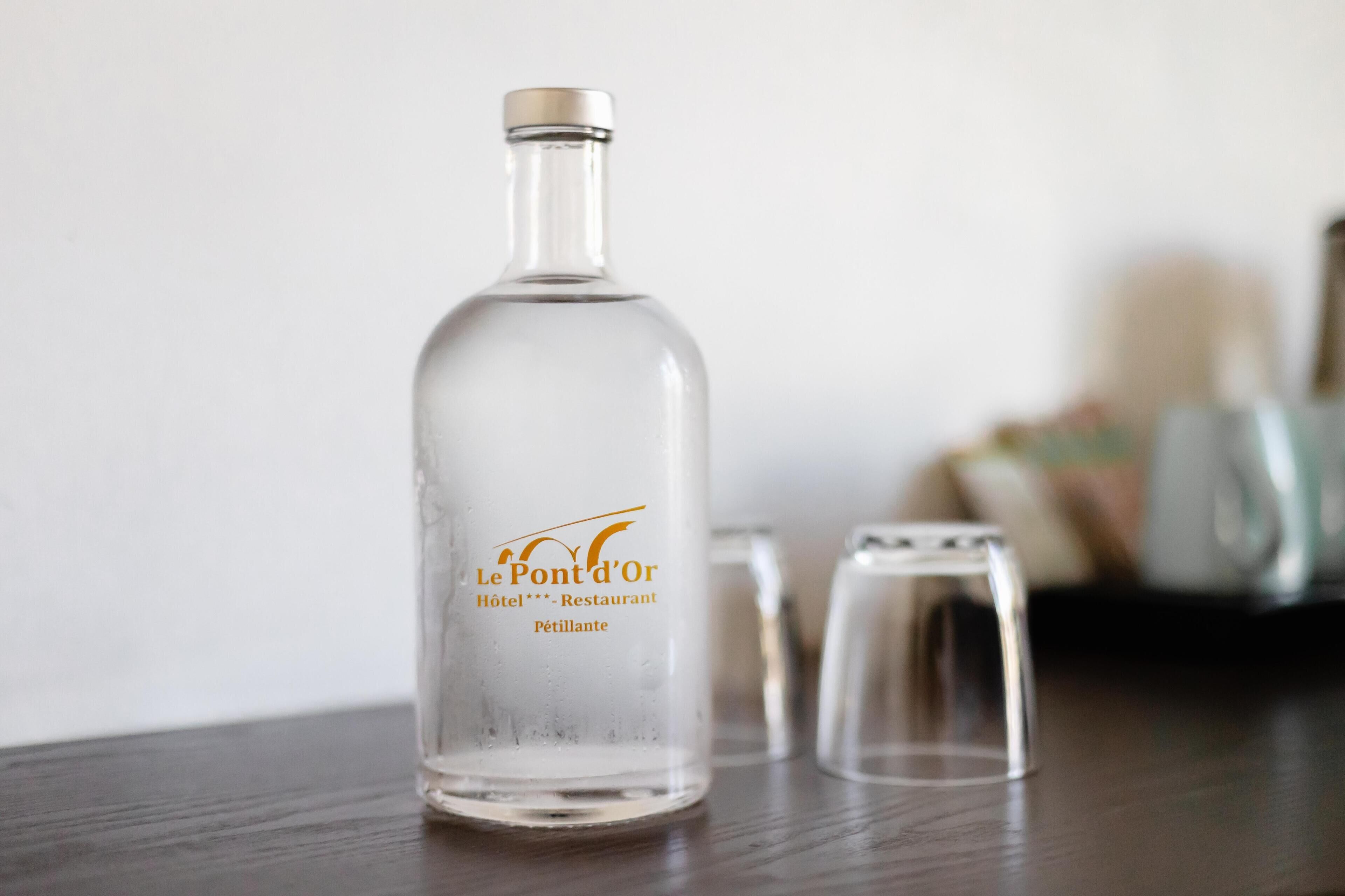 Una botella de vidrio transparente con una etiqueta sobre una superficie de madera.