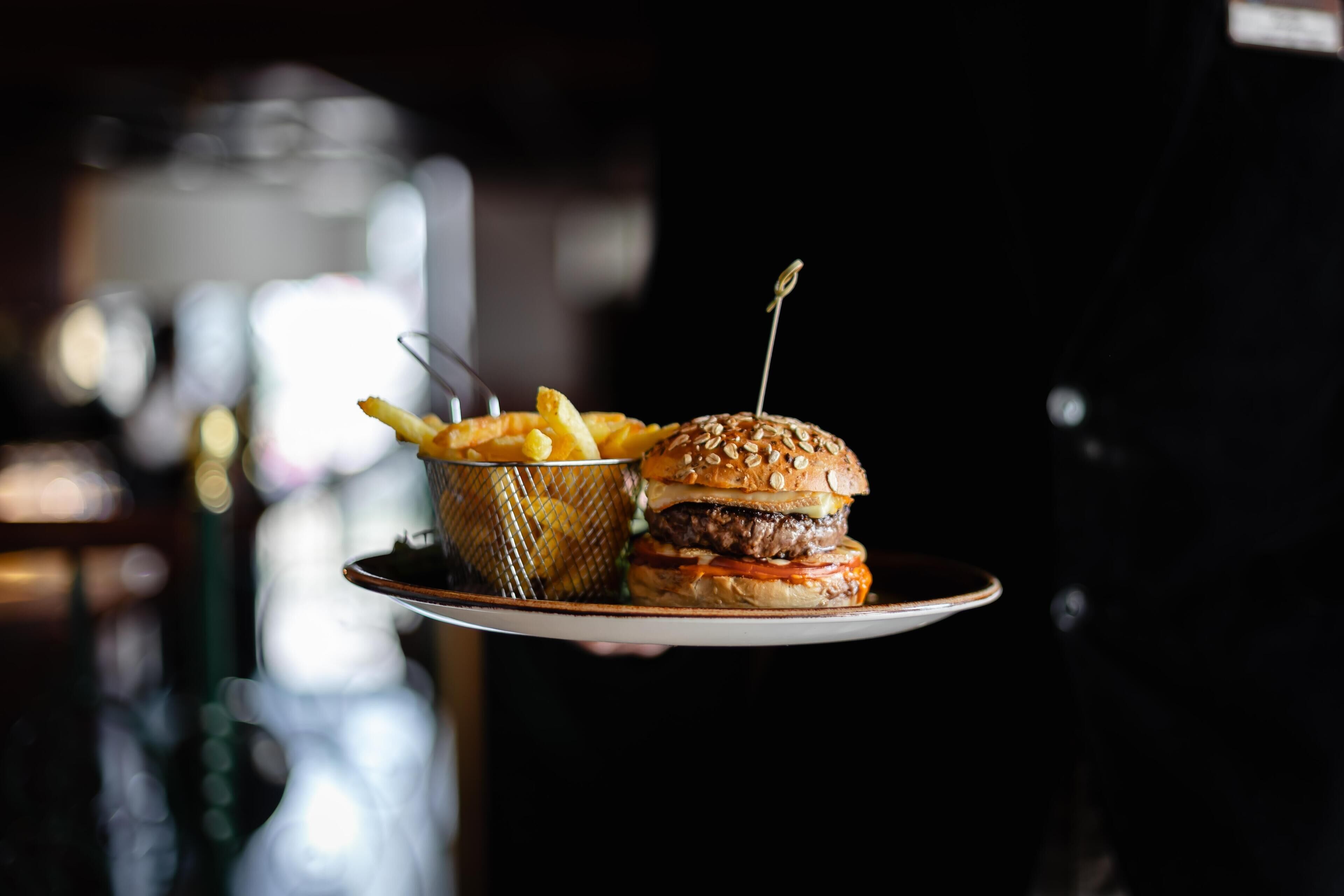 A person holding a plate with a burger and fries.